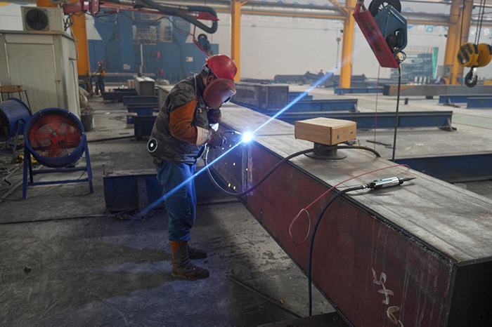 During the production process of steel structure bridges, workers weld steel box girder components using carbon dioxide gas shielded welding.